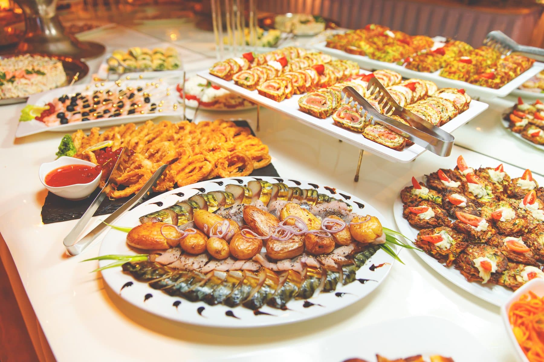 Aufgebautes Buffet mit Fischplatte, Ofenkartoffeln, gefüllten Auberginen und Kanapees